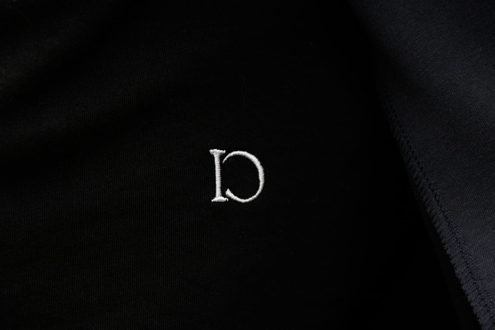 Close-up of the embroidered emblem on The Standard T-Shirt